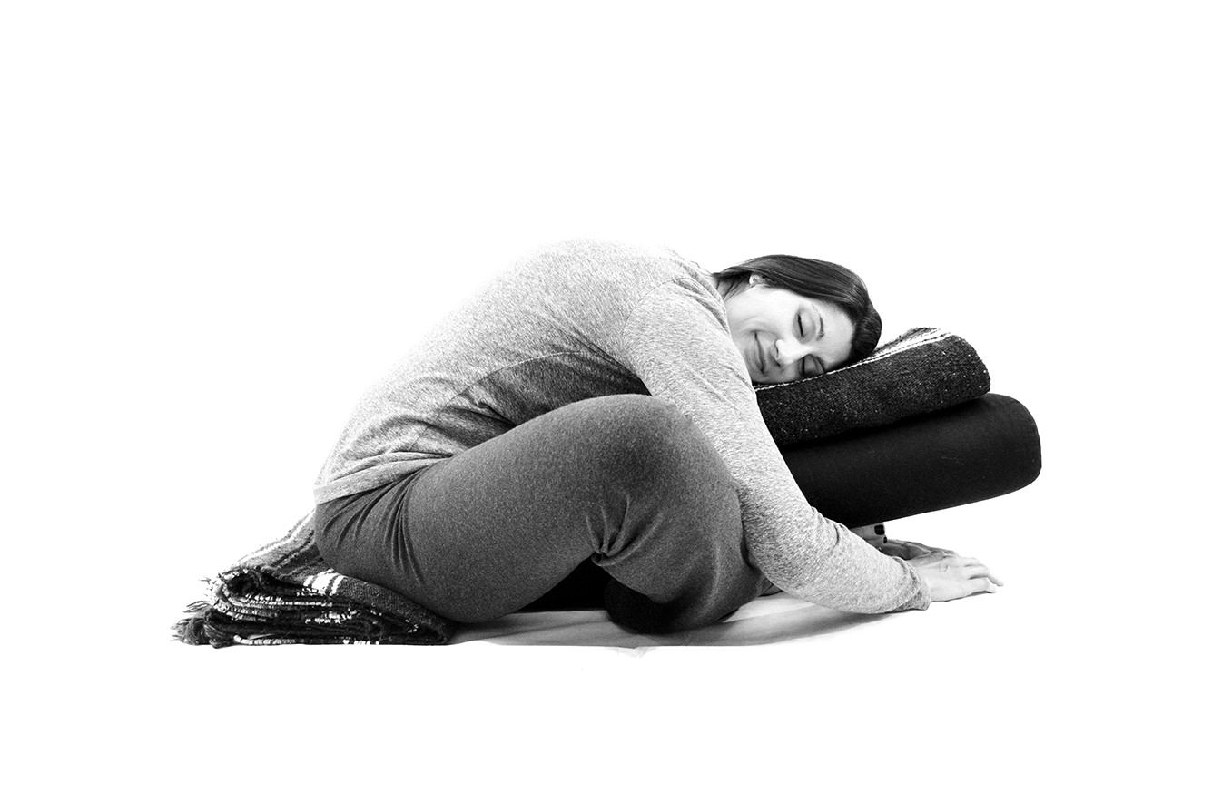 yoga for menstrual cramps - supported Resting Butterfly (seated on blanket, long rectangle fold, resting torso on bolster and blanket, long rectangle fold)